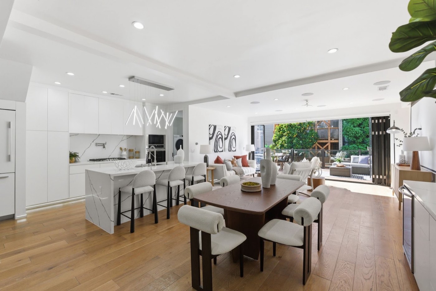 Open-plan remodeled kitchen and dining with waterfall island and folding doors to a deck